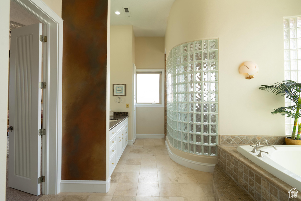 Bathroom featuring vanity, a bath, and tile patterned flooring