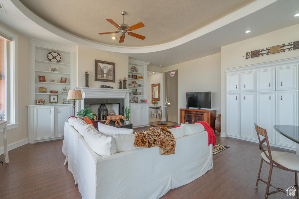 Living area with ceiling fan, dark wood-type flooring, built in shelves, a fireplace, and recessed lighting