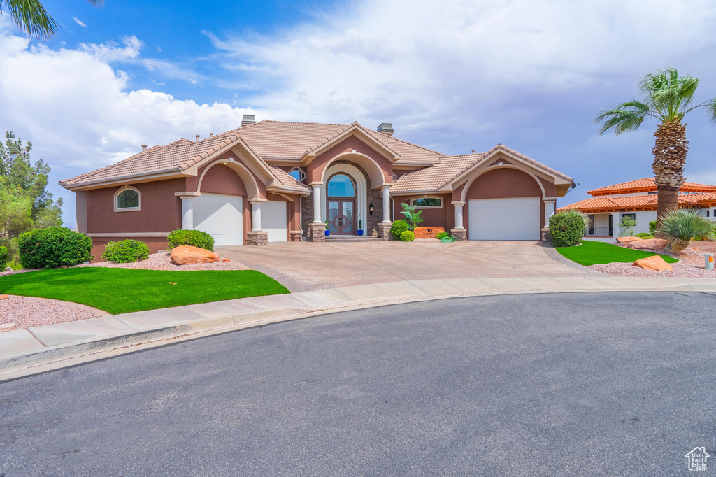Mediterranean / spanish-style home with a chimney, stucco siding, a tiled roof, and driveway