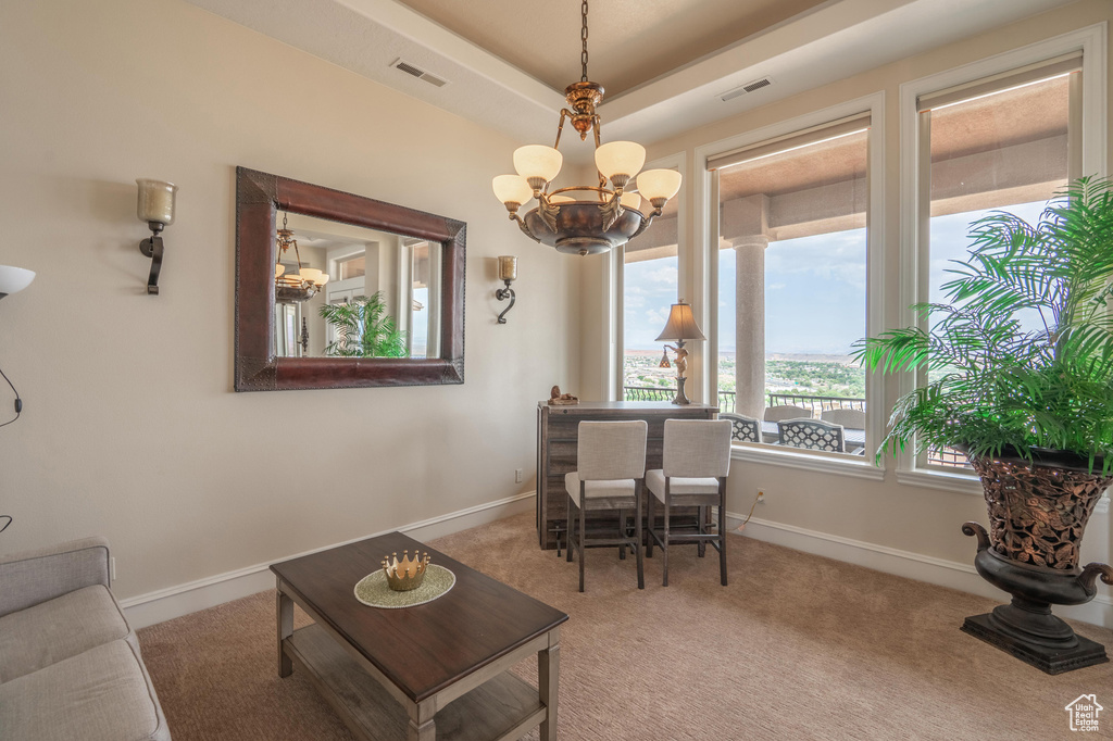 Carpeted living room featuring a chandelier and a raised ceiling