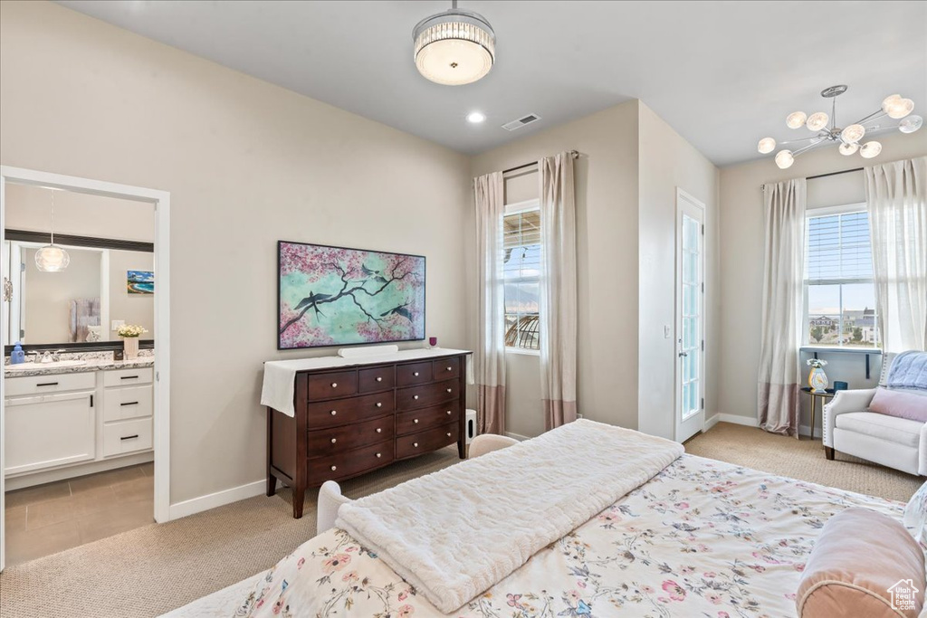 Bedroom with light colored carpet, a chandelier, and ensuite bathroom