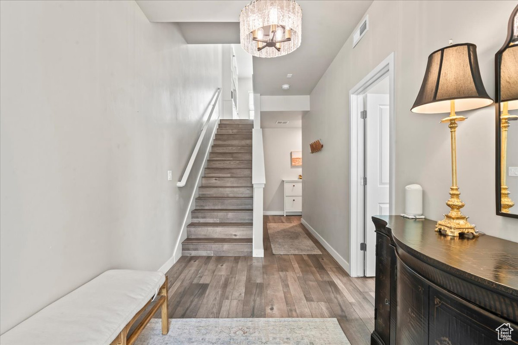 Stairs featuring a chandelier and wood finished floors