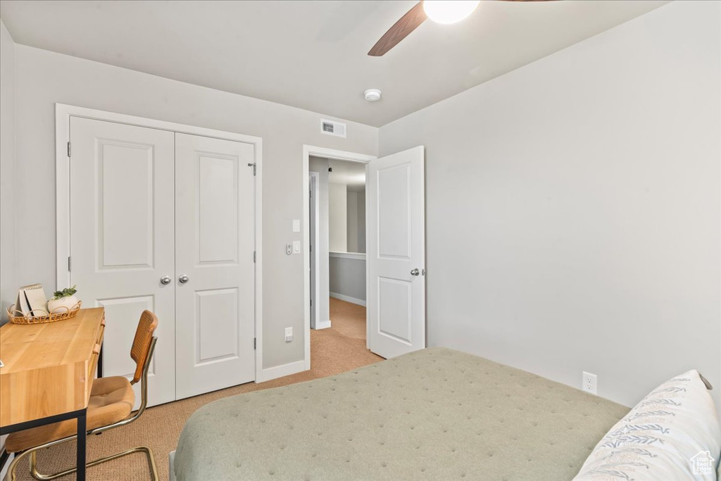 Bedroom featuring light carpet, a closet, and a ceiling fan
