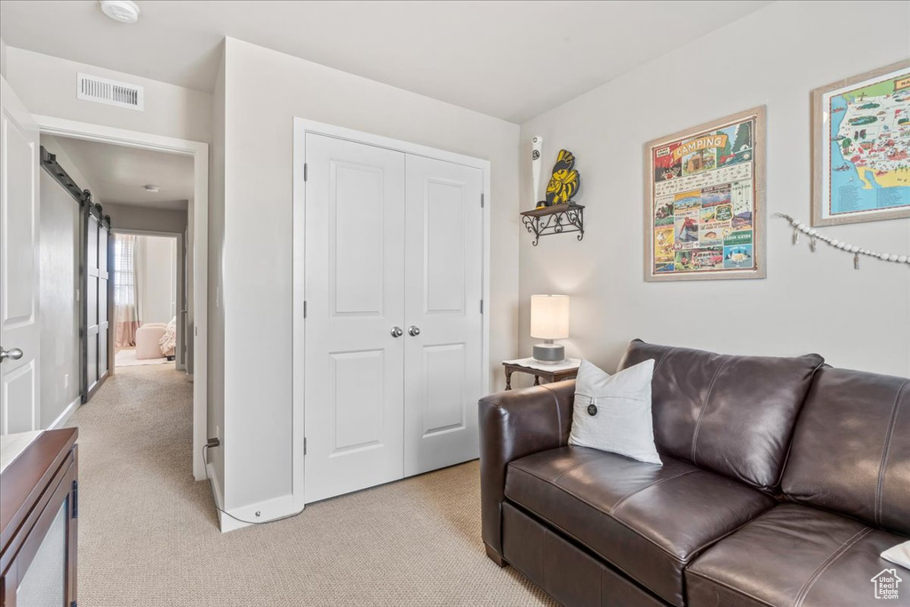 Living room featuring light colored carpet and a barn door