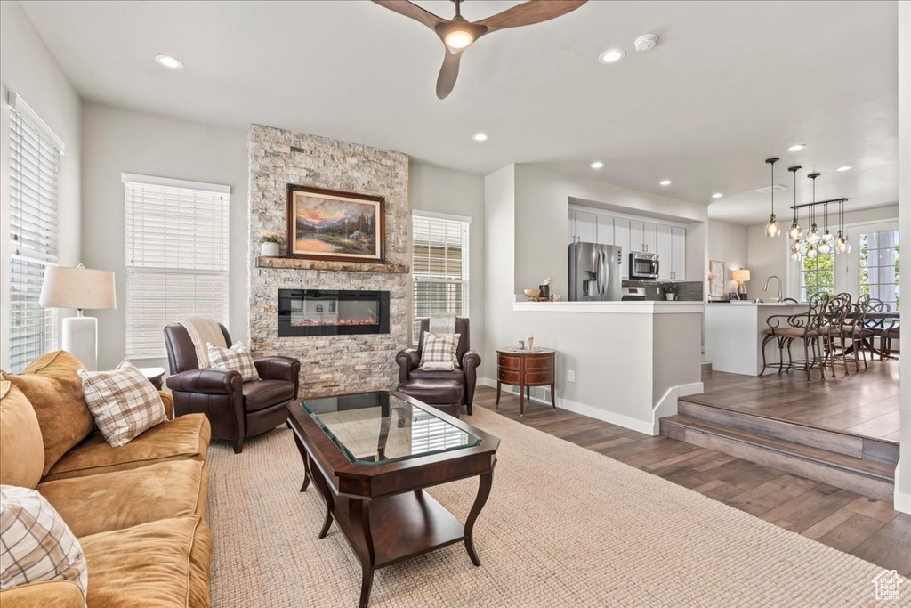 Living area with light wood finished floors, a ceiling fan, a fireplace, and recessed lighting