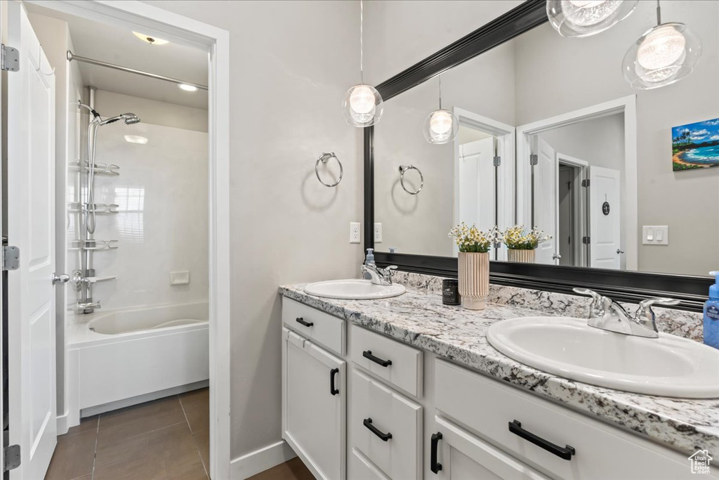 Full bath featuring double vanity, tile patterned floors, and shower / washtub combination