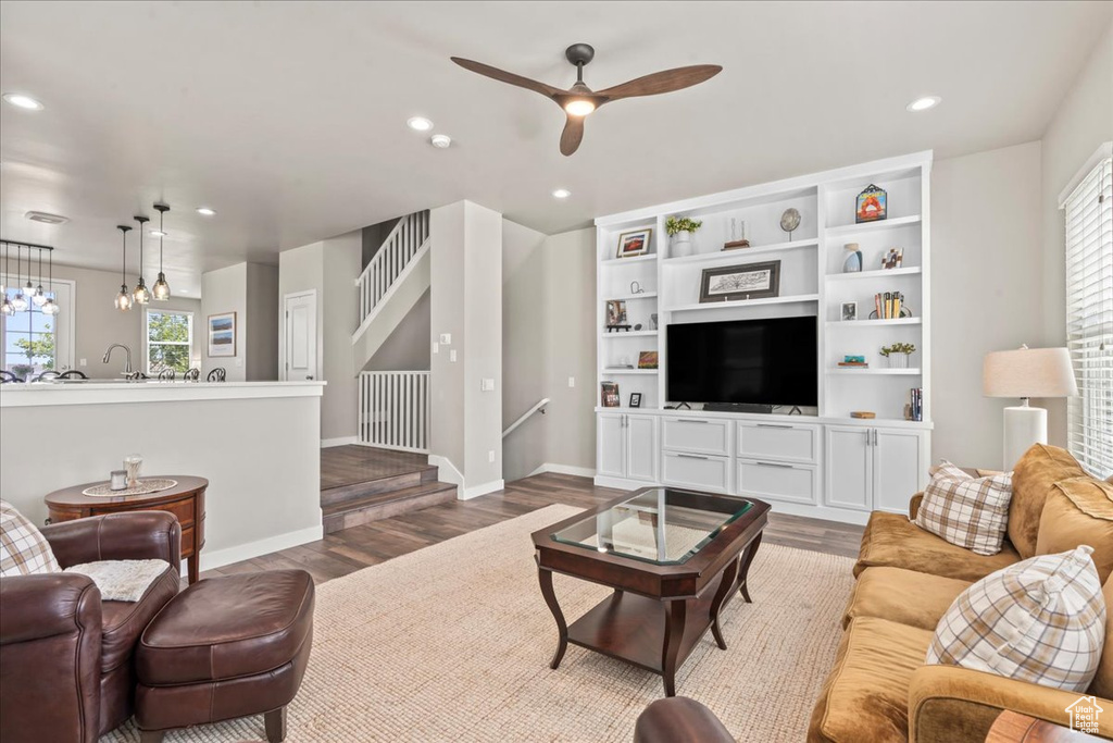 Living room with healthy amount of natural light, wood finished floors, ceiling fan, recessed lighting, and a chandelier
