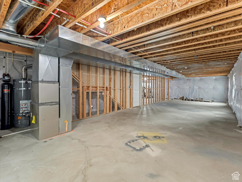 Unfinished basement featuring strapped water heater and heating unit