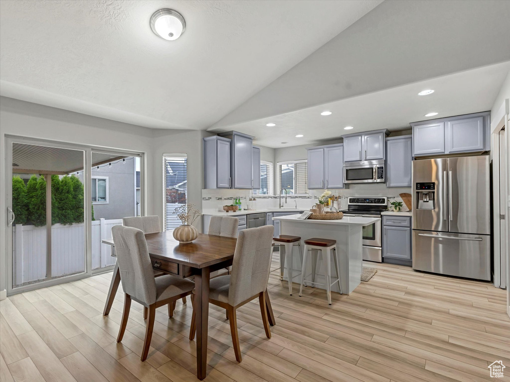 Dining room with vaulted ceiling, light wood finished floors, and recessed lighting