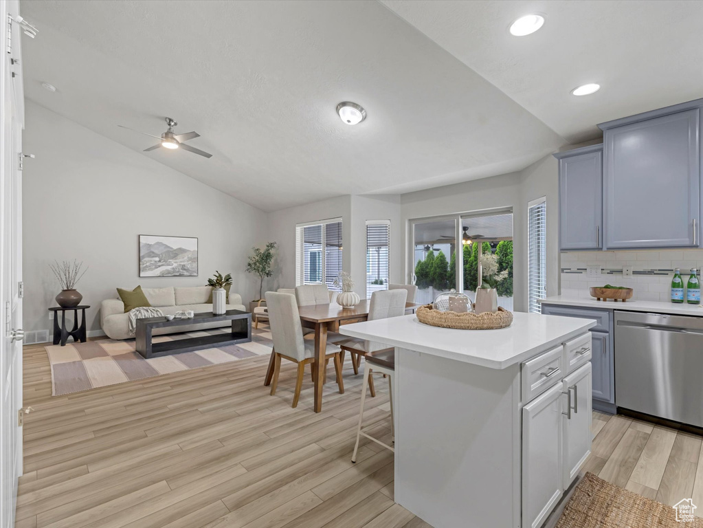 Kitchen featuring dishwasher, vaulted ceiling, light countertops, light wood finished floors, and backsplash