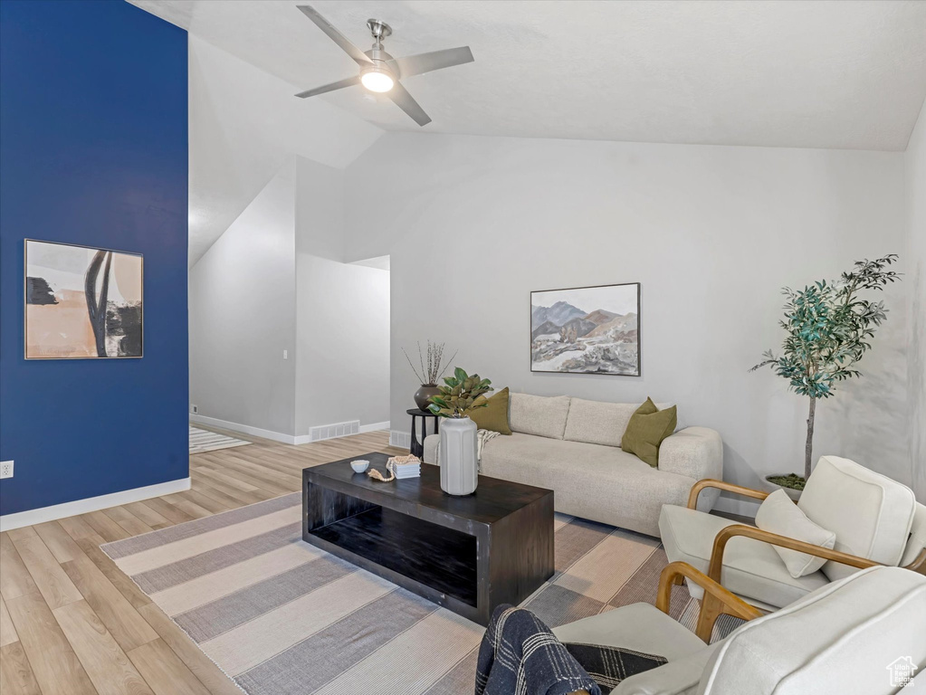 Living room featuring lofted ceiling, wood finished floors, and a ceiling fan