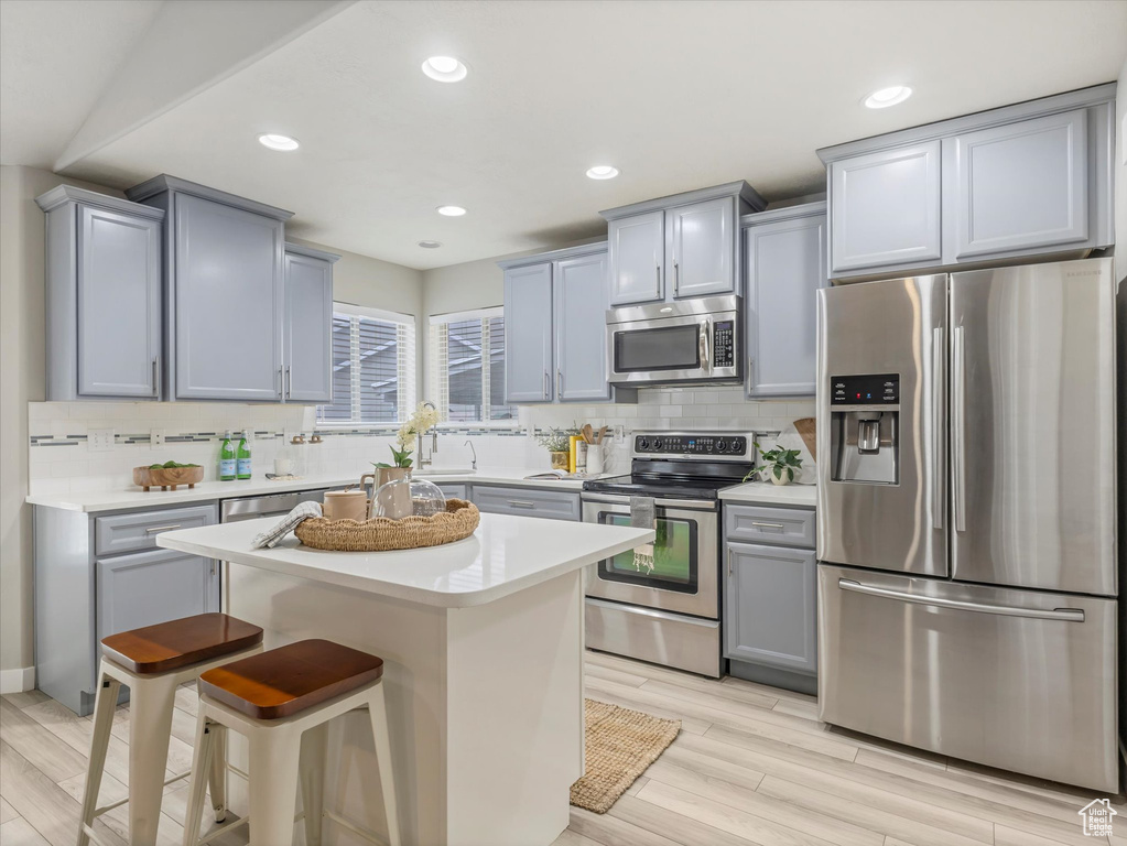 Kitchen featuring appliances with stainless steel finishes, tasteful backsplash, gray cabinetry, and recessed lighting