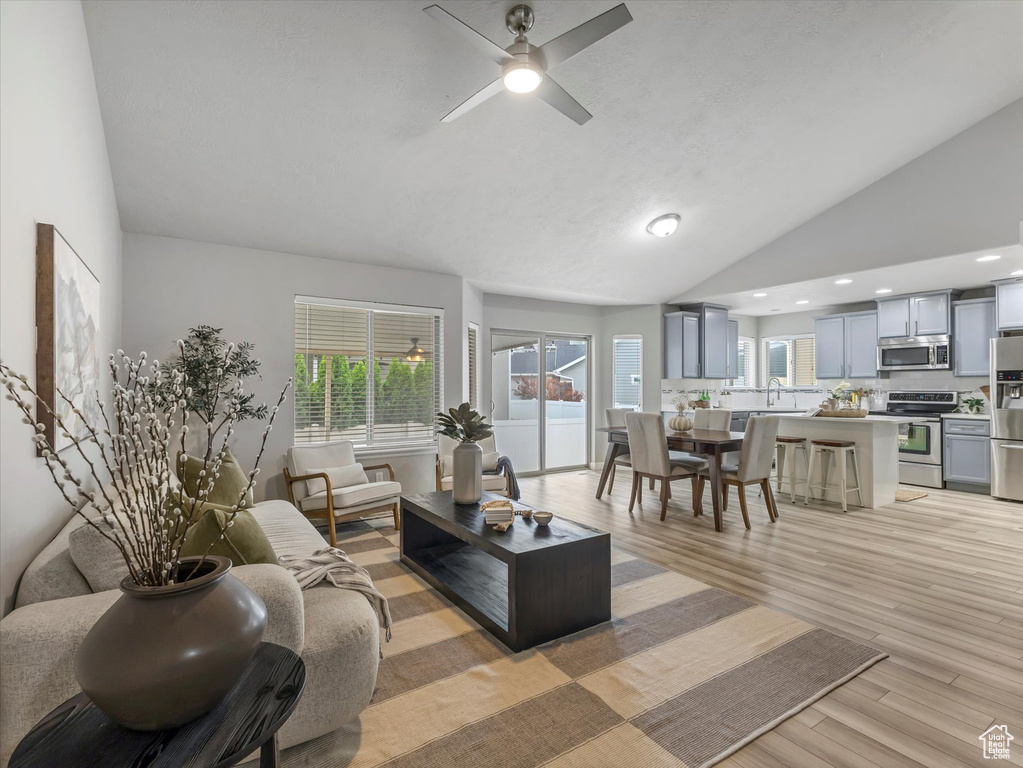 Living area featuring light wood-type flooring, ceiling fan, healthy amount of natural light, recessed lighting, and high vaulted ceiling