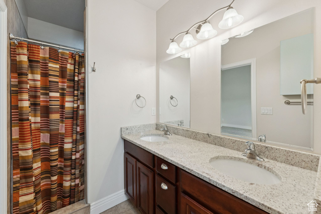 Bathroom featuring double vanity, tile patterned floors, and a shower with shower curtain