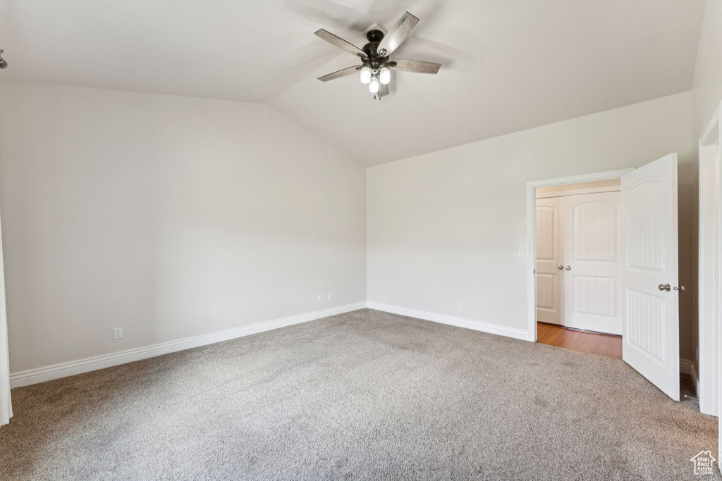 Unfurnished bedroom featuring carpet, lofted ceiling, and a ceiling fan