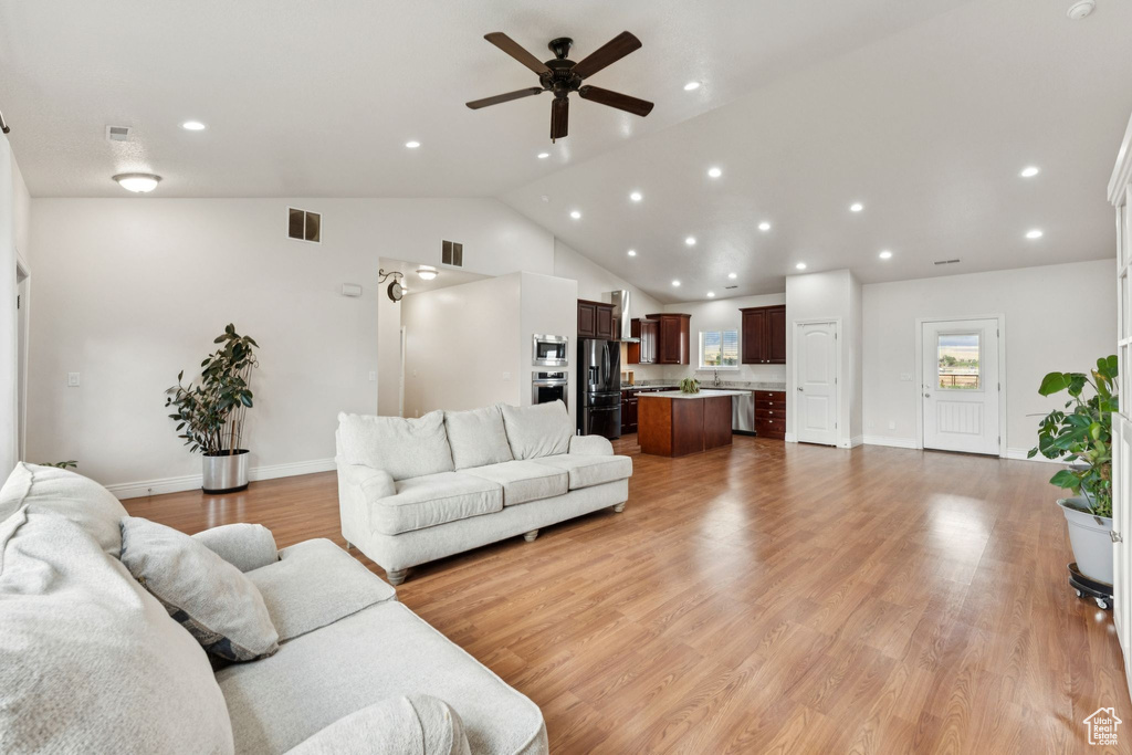 Living area featuring a ceiling fan, light wood-type flooring, vaulted ceiling, and recessed lighting