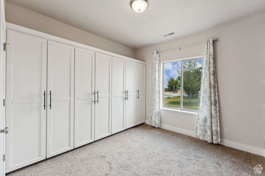Unfurnished bedroom featuring light colored carpet and a closet