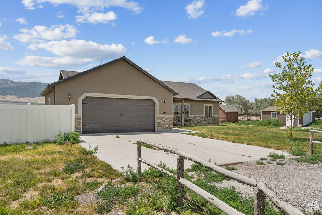 View of front of house with a garage, stone siding, concrete driveway, and stucco siding