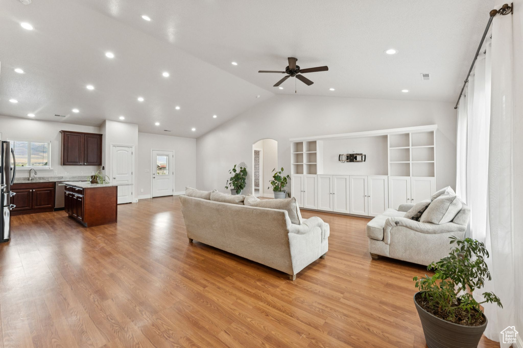 Living room with arched walkways, vaulted ceiling, recessed lighting, light wood-type flooring, and ceiling fan