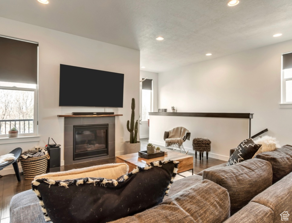 Living area with recessed lighting, wood finished floors, and a tiled fireplace