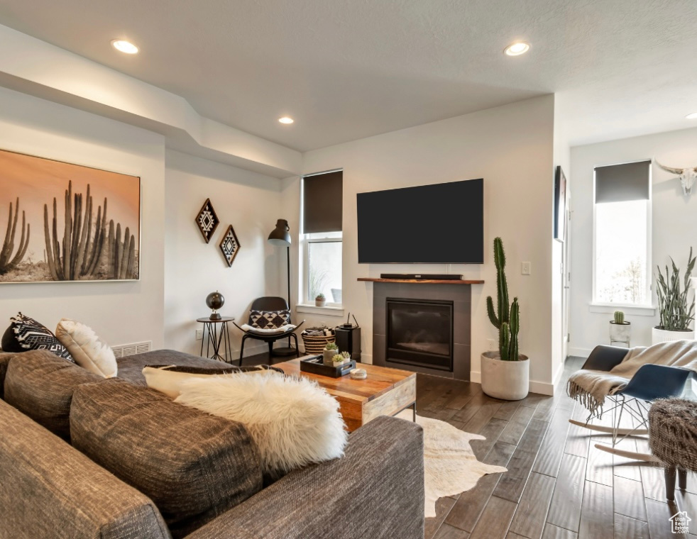 Living area with recessed lighting, dark wood-style flooring, and a glass covered fireplace