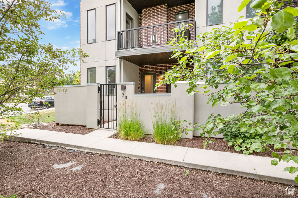 Property entrance with a balcony, a gate, and brick siding