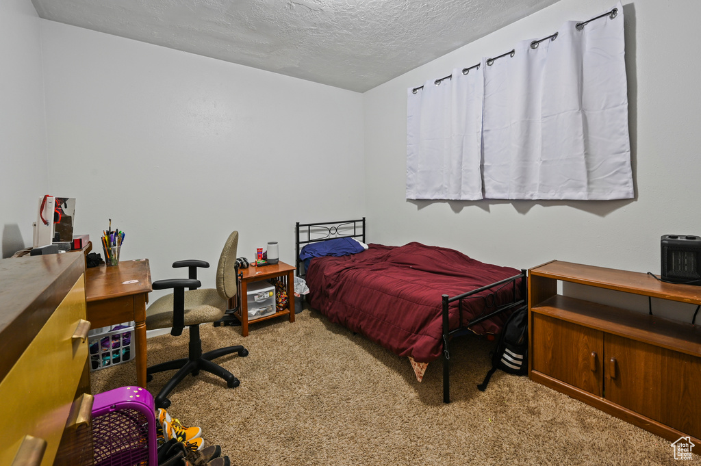 Bedroom with carpet flooring, an office area, and a textured ceiling