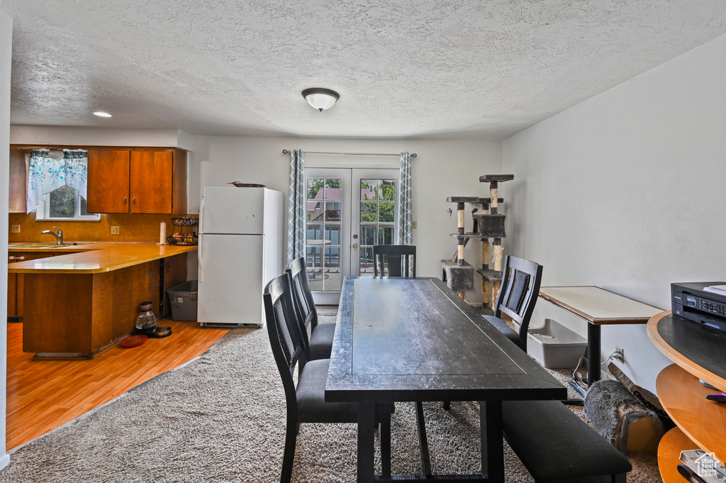 Dining space featuring light wood-style floors, french doors, and a textured ceiling