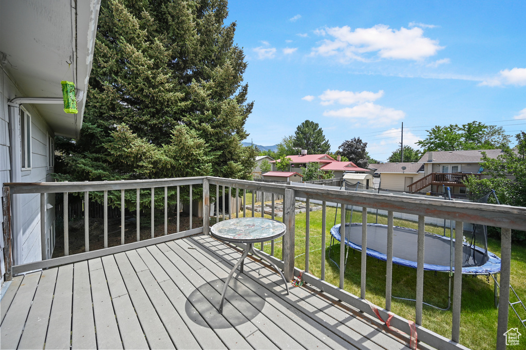 Wooden deck with a trampoline, a residential view, and a yard