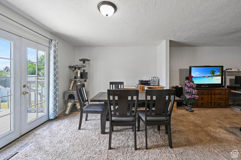 Dining room featuring carpet flooring, a textured ceiling, and french doors