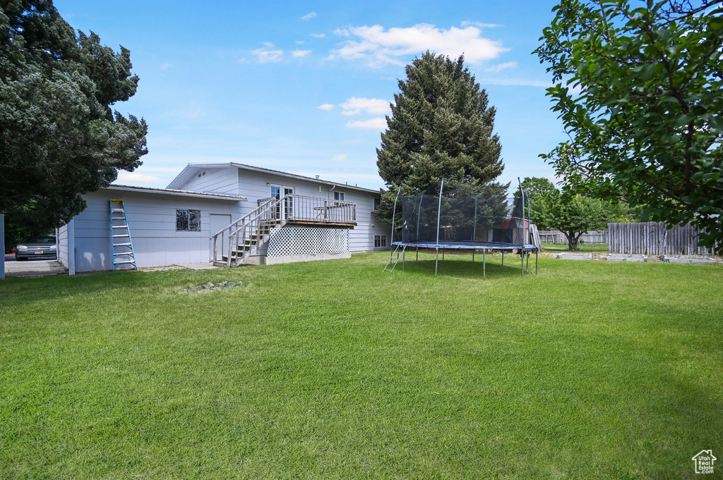 View of yard with stairway, a trampoline, and a deck