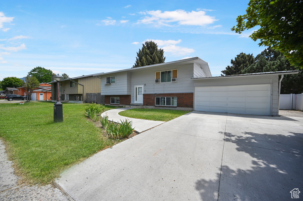 Raised ranch featuring concrete driveway, a garage, and brick siding