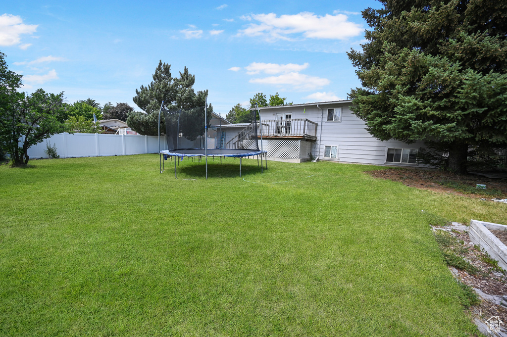 View of yard with a trampoline and a wooden deck
