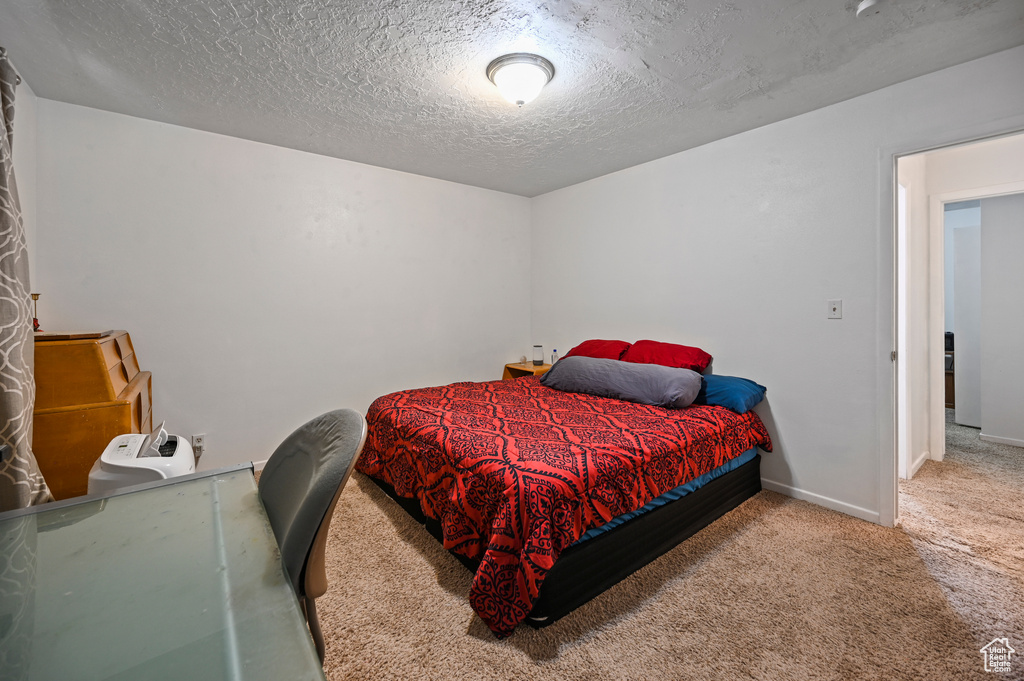 Carpeted bedroom with a textured ceiling and baseboards