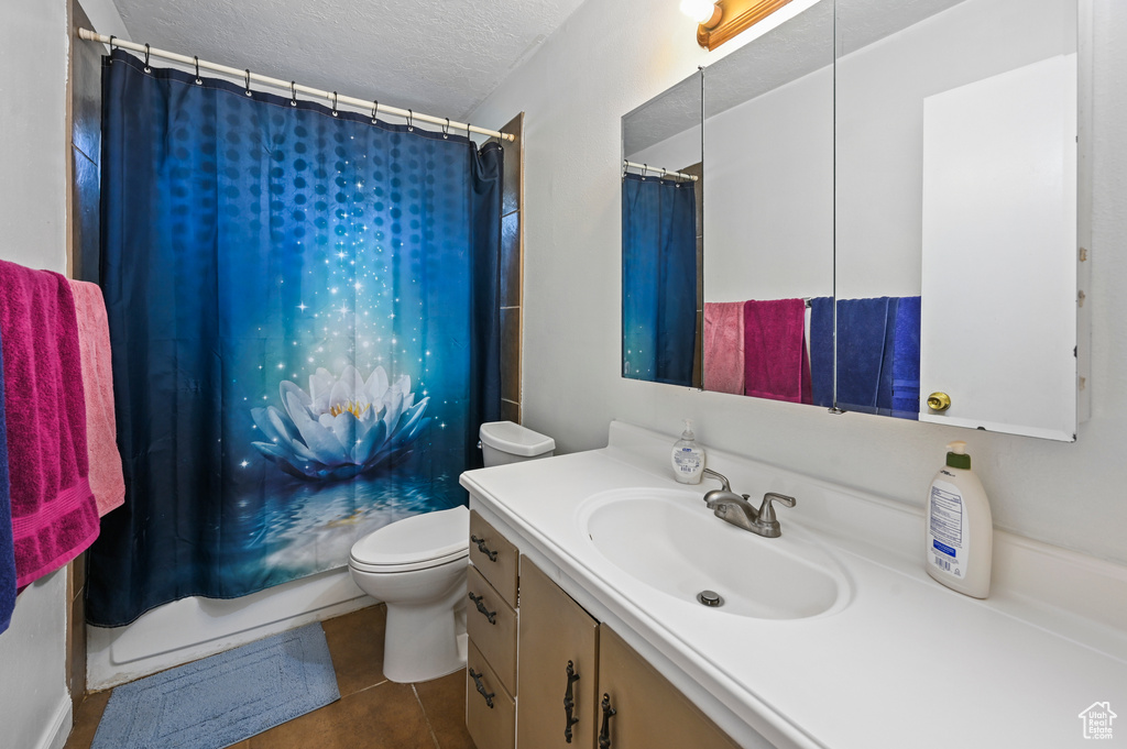 Full bathroom featuring vanity, tile patterned floors, a textured ceiling, and a shower with shower curtain