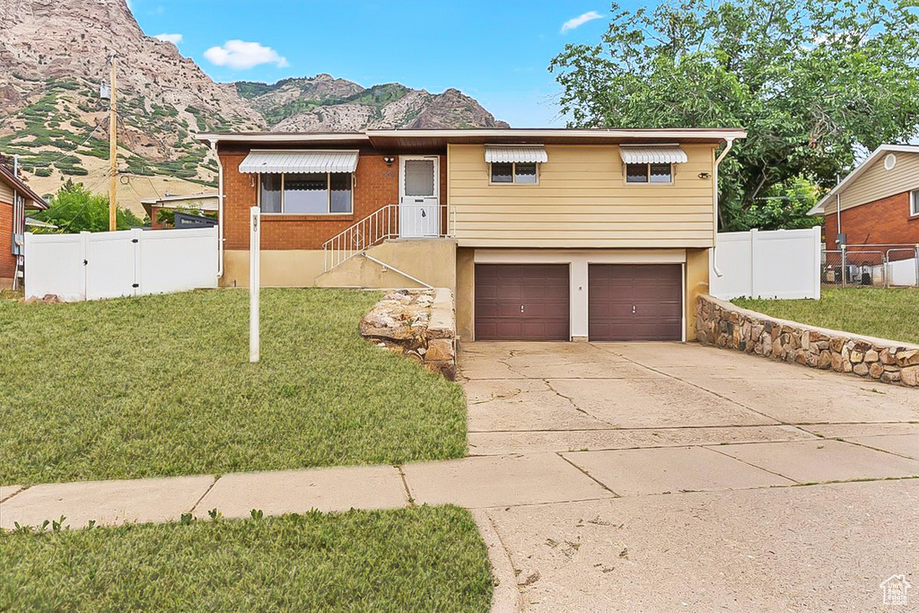 Ranch-style house featuring an attached garage, a mountain view, driveway, and a gate