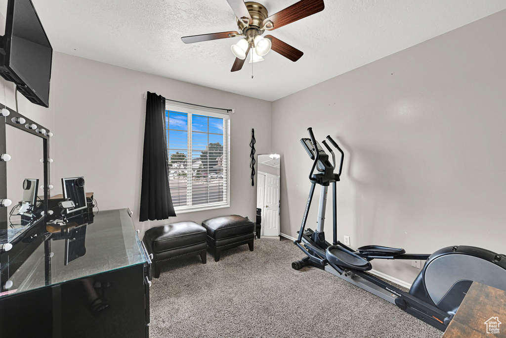 Workout area with ceiling fan, a textured ceiling, and carpet flooring