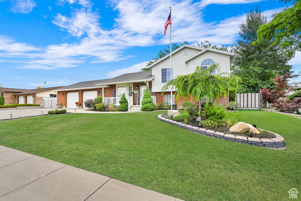 Split level home featuring concrete driveway, an attached garage, and brick siding