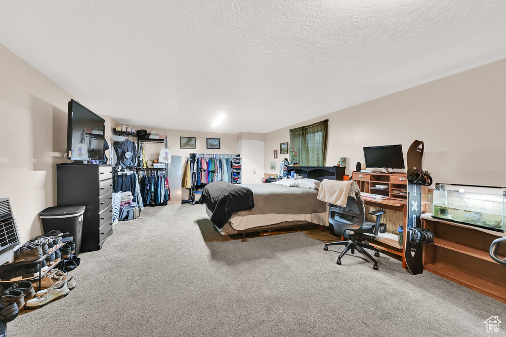 Carpeted bedroom featuring an office area and a textured ceiling
