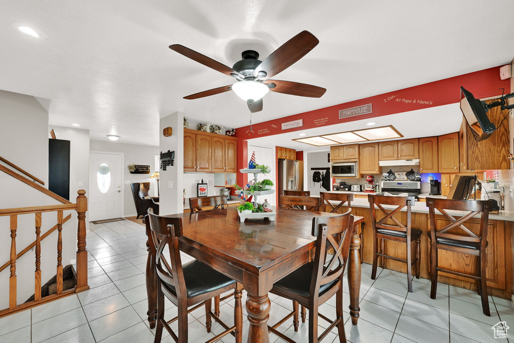 Dining room with ceiling fan, light tile patterned flooring, recessed lighting, and stairway