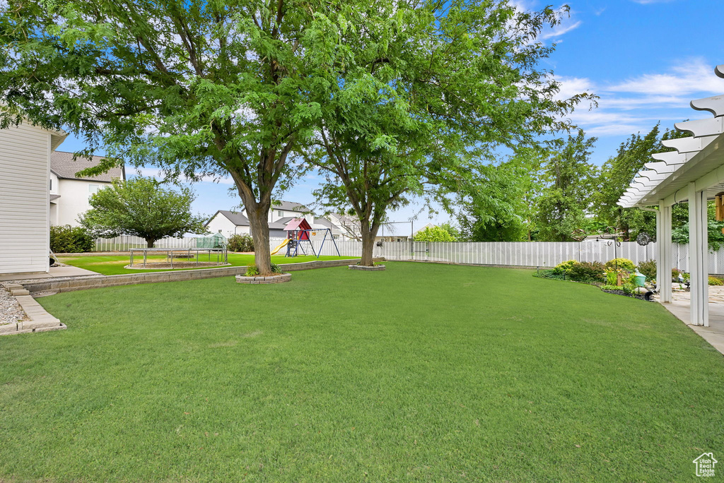 Fenced backyard featuring a playground