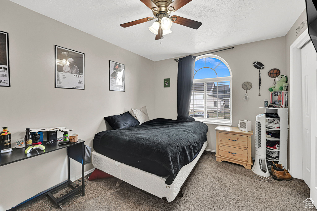 Bedroom with carpet flooring, ceiling fan, and a textured ceiling