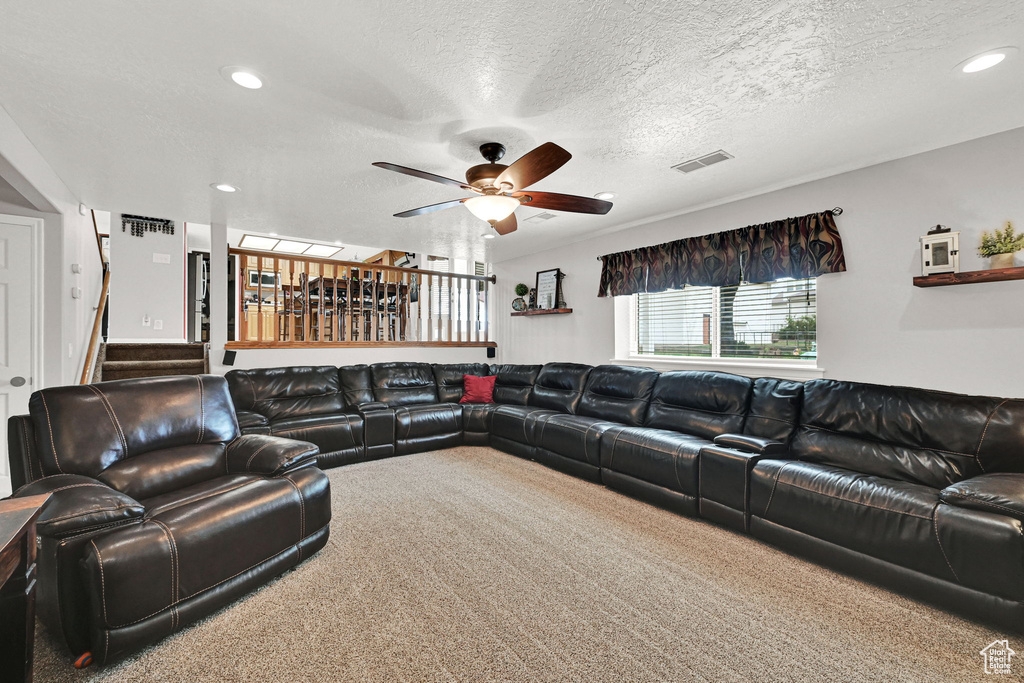 Living room featuring carpet, a ceiling fan, a textured ceiling, stairway, and recessed lighting