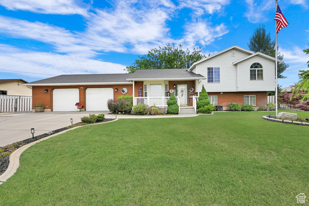 Split level home featuring brick siding, a porch, driveway, and an attached garage