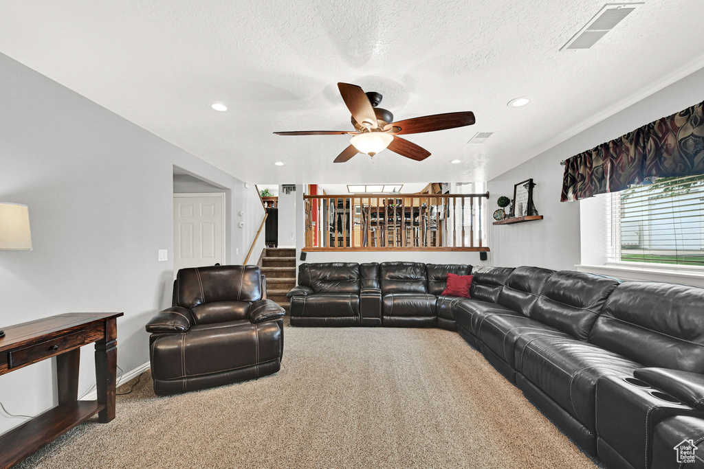 Carpeted living room with ceiling fan, stairs, recessed lighting, and a textured ceiling
