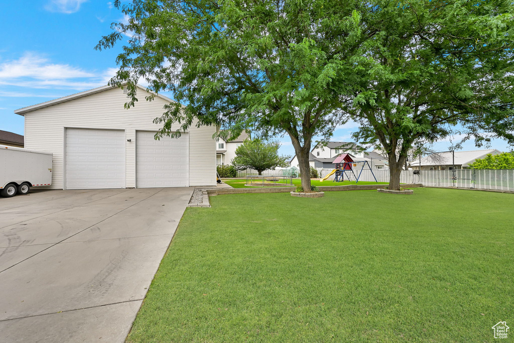 View of yard featuring a playground, a garage, and an outbuilding
