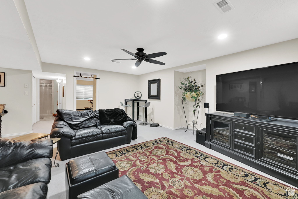Carpeted living area with ceiling fan and recessed lighting