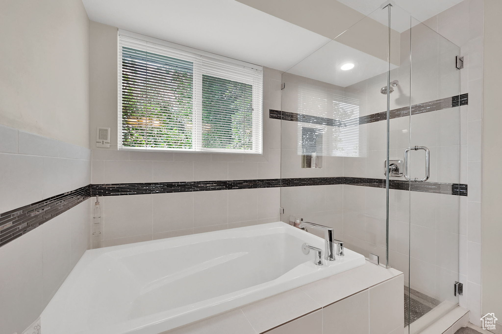 Full bathroom with a bath, tile walls, and a shower stall