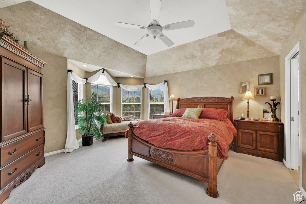 Bedroom with light carpet, vaulted ceiling, and a ceiling fan