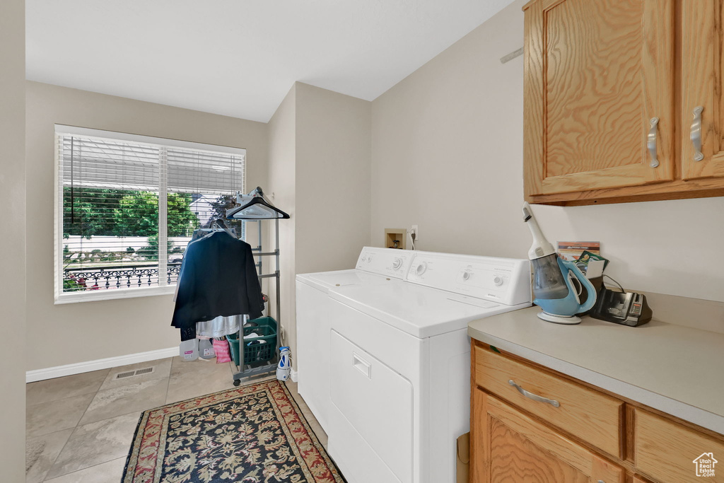 Laundry room with cabinet space, light tile patterned flooring, and separate washer and dryer